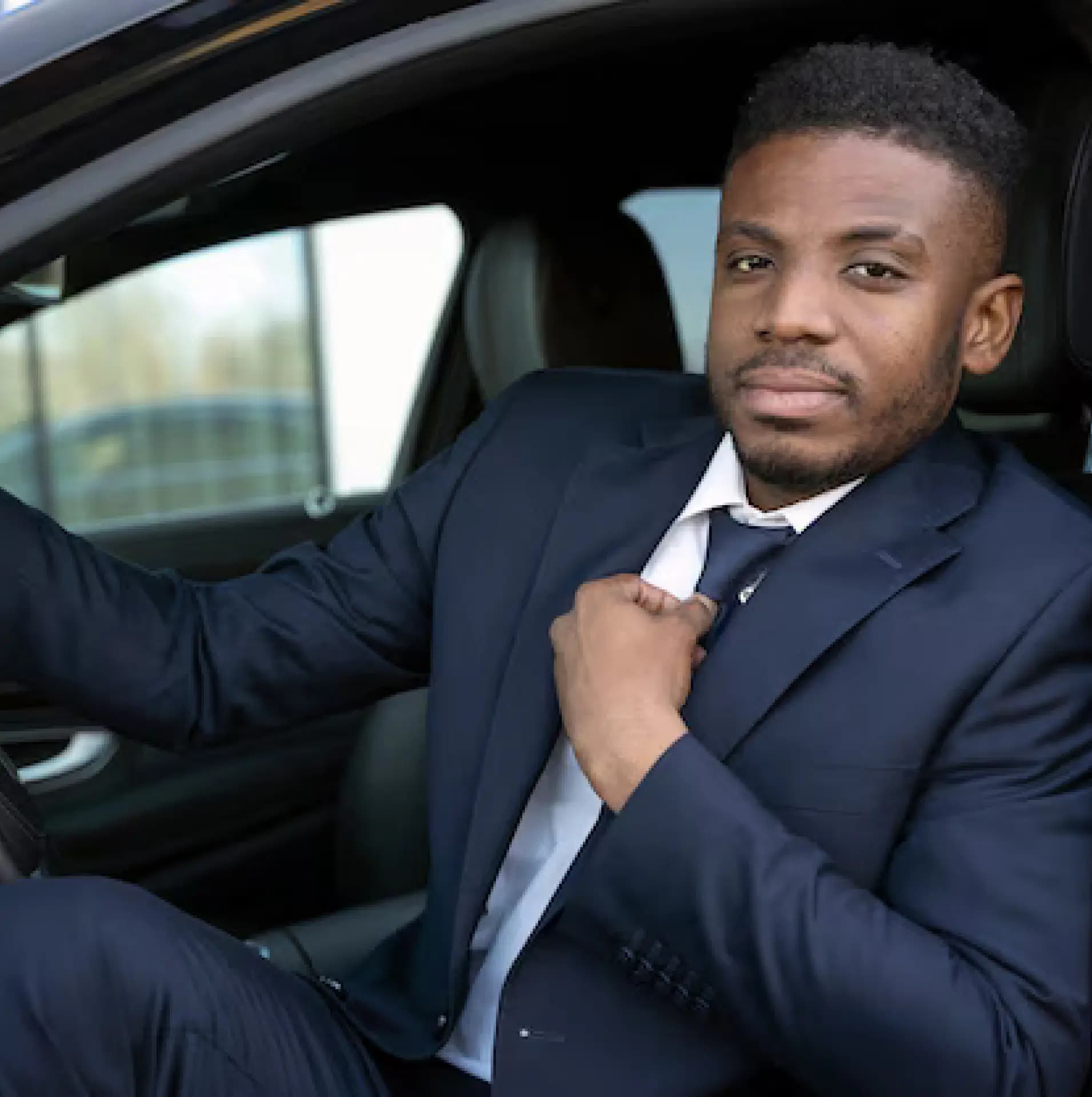 Professional driver in business attire adjusting tie in car