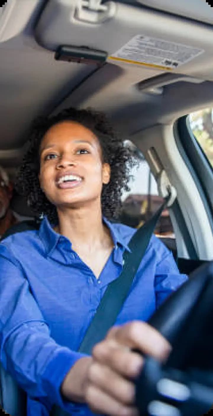 Person in blue attire driving car with enthusiastic expression